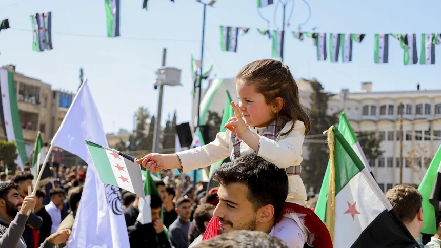 Ein Mädchen sitzt auf den Schultern eines Mannes und schwenkt eine syrische Oppositionsflagge während einer Kundgebung in Idlib, Syrien, 
